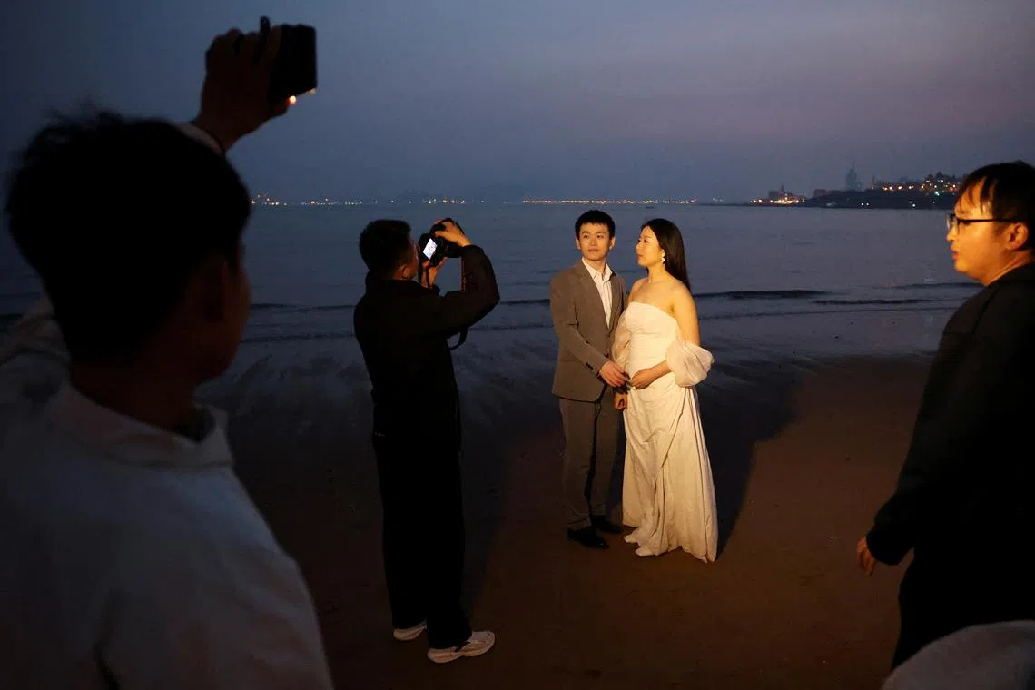 FILE PHOTO: A couple poses for a pre-wedding photoshoot after sunset on a beach in Qingdao, Shandong province, China April 21, 2024. REUTERS/Florence Lo/File Photo