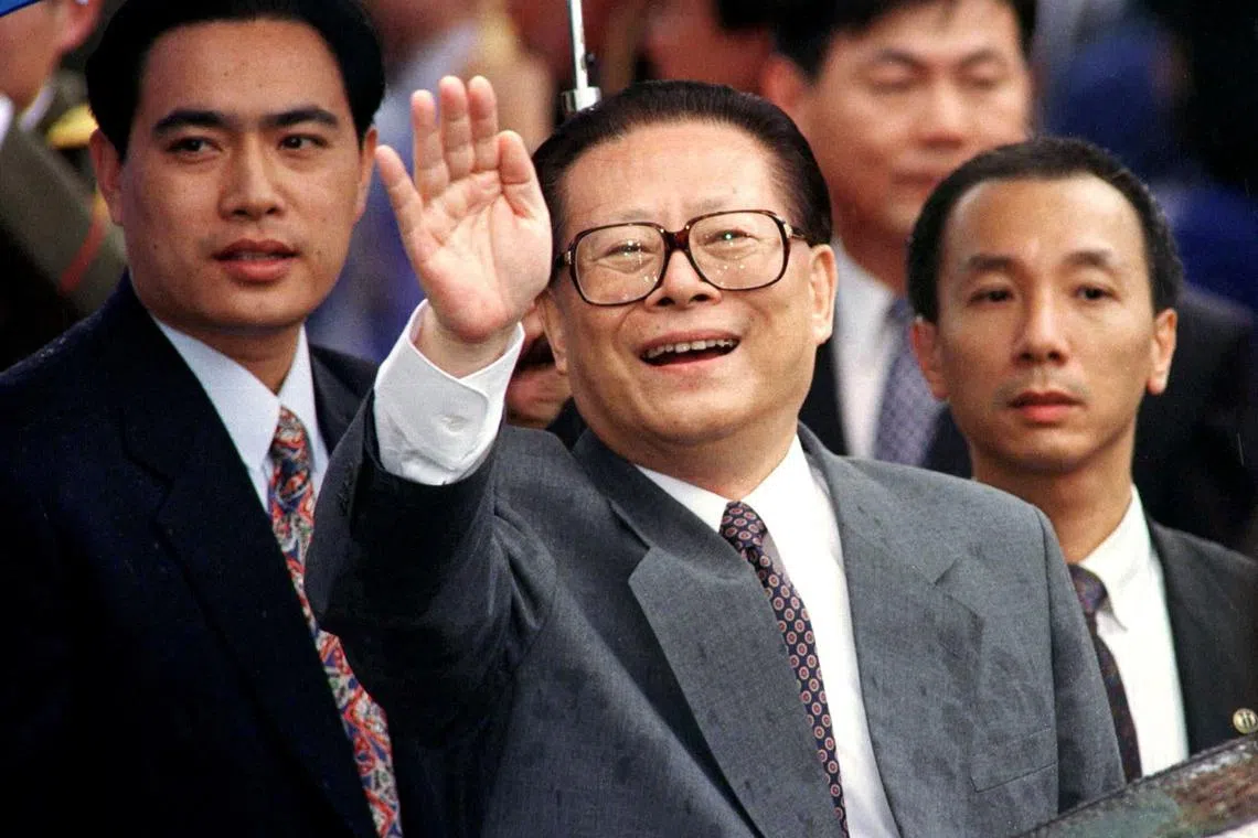 Chinese President Jiang Zemin smiles through the rain and waves to a crowd upon his arrival in Hong Kong on June 30, 1997. 