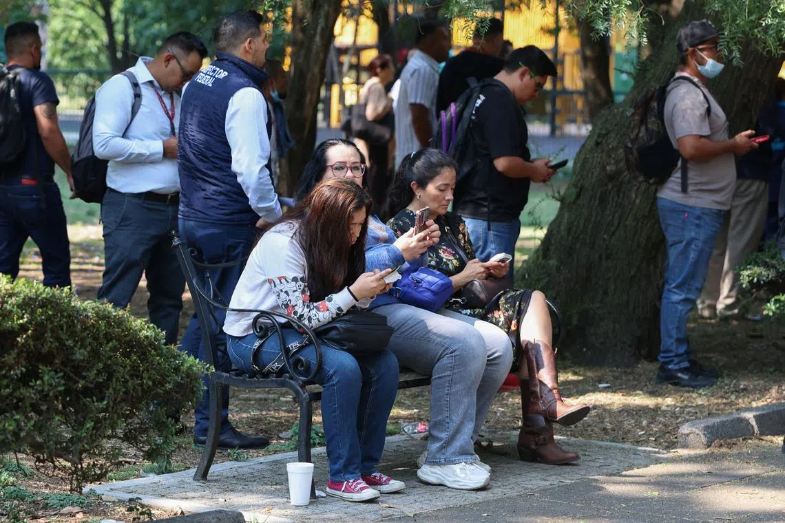 People sit on a bench while they wait outside, after an earthquake alarm sounded warning of a tremor, in Mexico City, Mexico, May 4, 2026. REUTERS/Luis Cortes