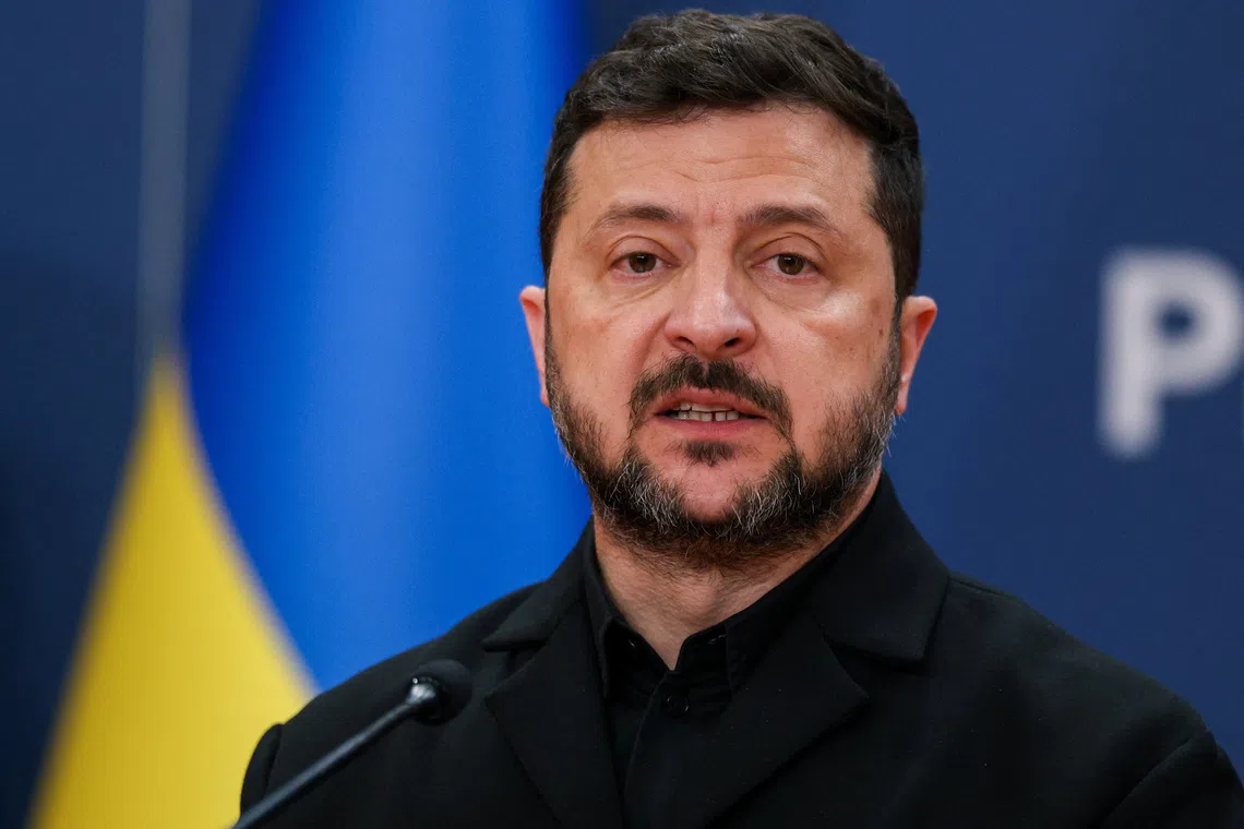 A man speaking at a podium with a blue and yellow flag behind him.