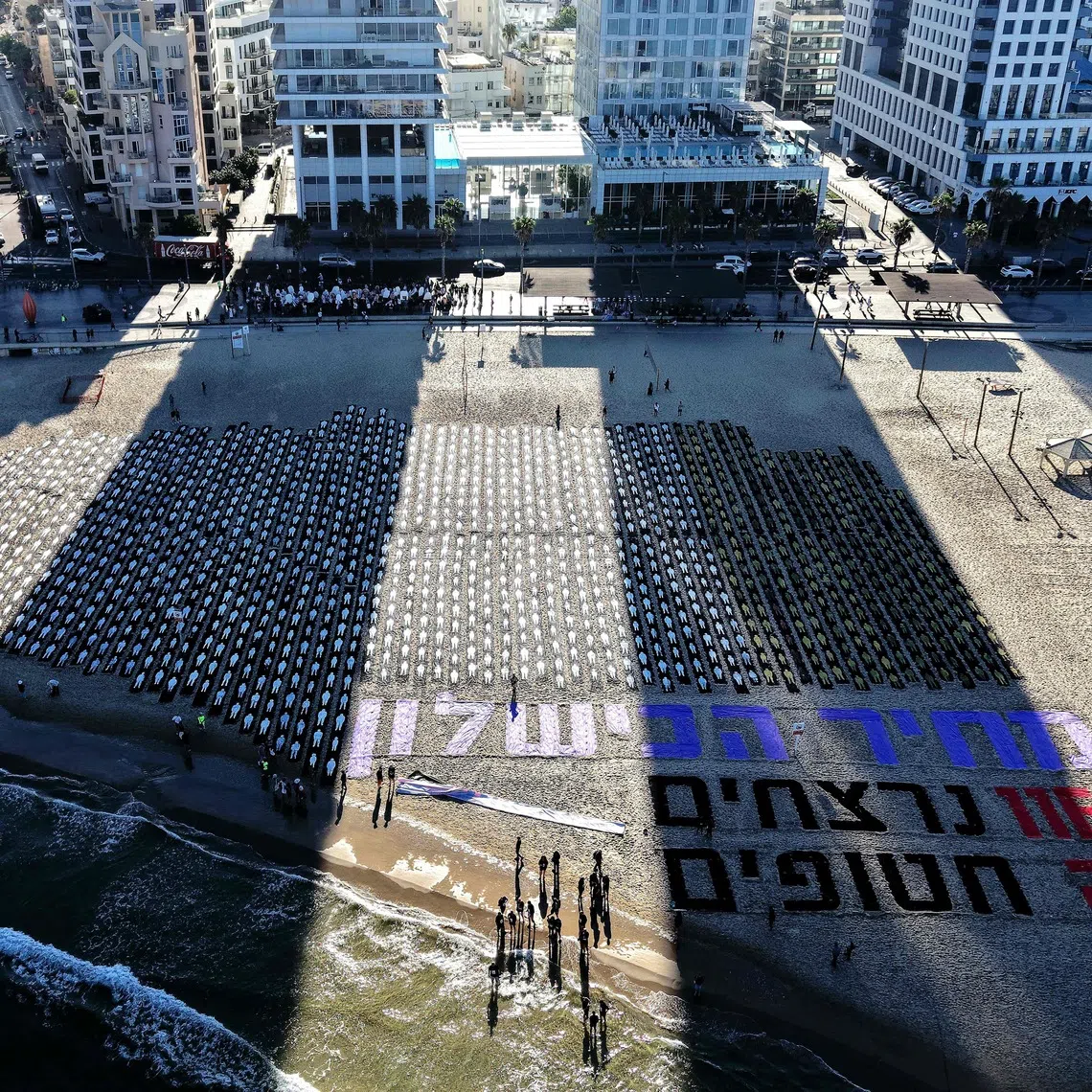 An aerial view shows people gathering around a commemorative installation marking the third anniversary of Hamas's October 7 attack on Israel, in Tel Aviv on October 7, 2026. Israel marked the third anniversary of Hamas's October 7 attack with silent tributes, new strikes on Gaza and intense political debate, weeks before elections in which the country's deadliest day will be front and centre. (Photo by Jack GUEZ / AFP)