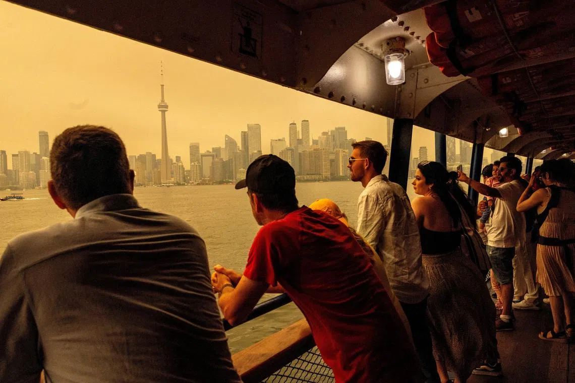 People ride the ferry to Toronto Island, as wildfire smoke from northwestern Ontario fills the sky, in Ontario, Canada, on July 15.