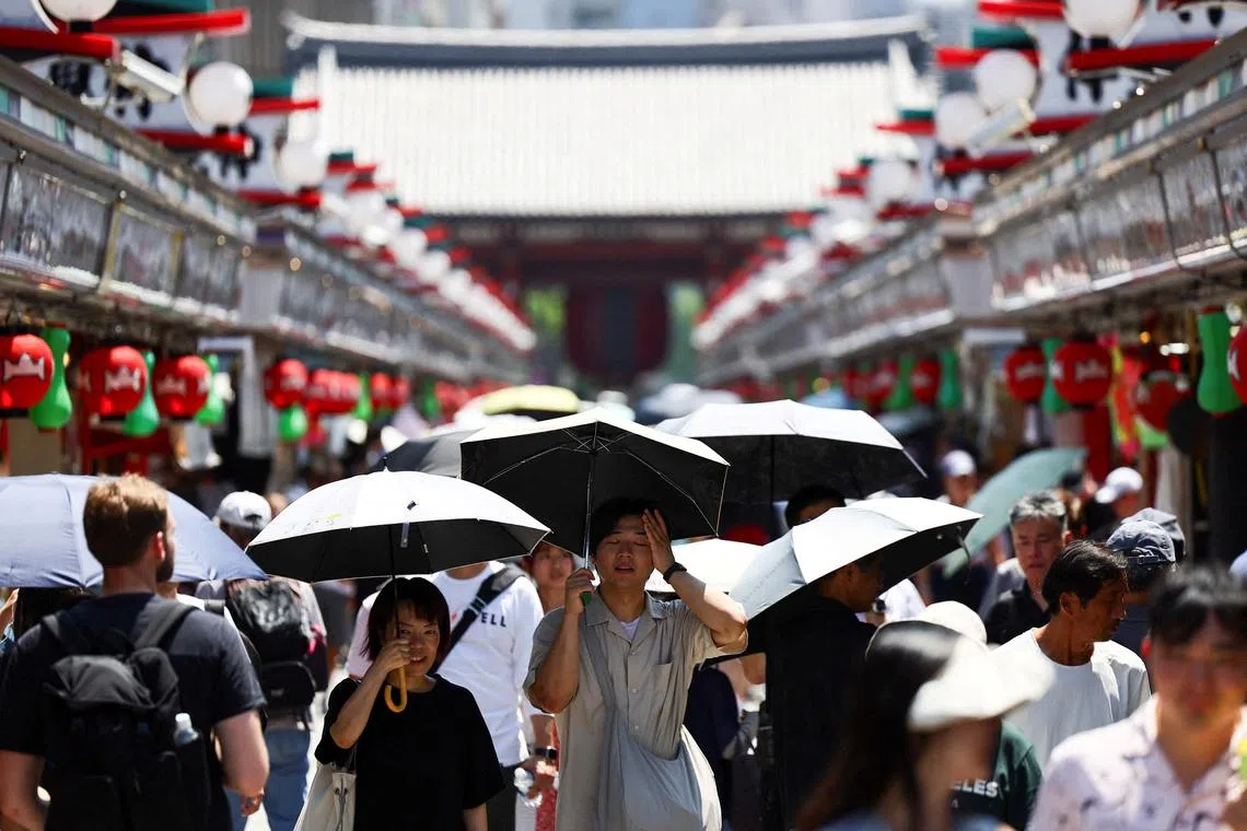 Visitors holding parasols walk along Nakamise street at the Asakusa district, a popular sightseeing spot, as the Japanese government issued a heatstroke alert in Tokyo and other prefectures due to a heatwave, in Tokyo, Japan August 5, 2025.  REUTERS/Issei Kato