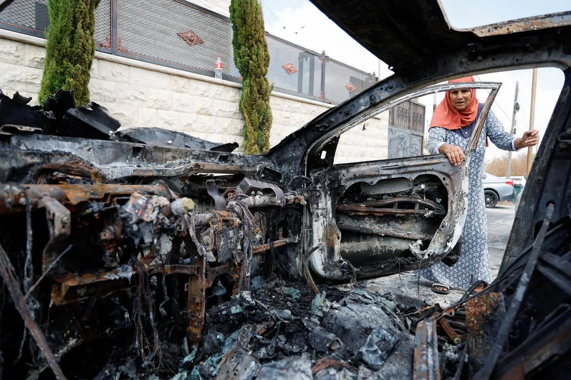 FILE PHOTO: A Palestinian woman inspects a vehicle destroyed during an Israeli settlers' attack in the village of Jeit, near Qalqilya in the Israeli-occupied West Bank August 16, 2024. REUTERS/Raneen Sawafta/File Photo