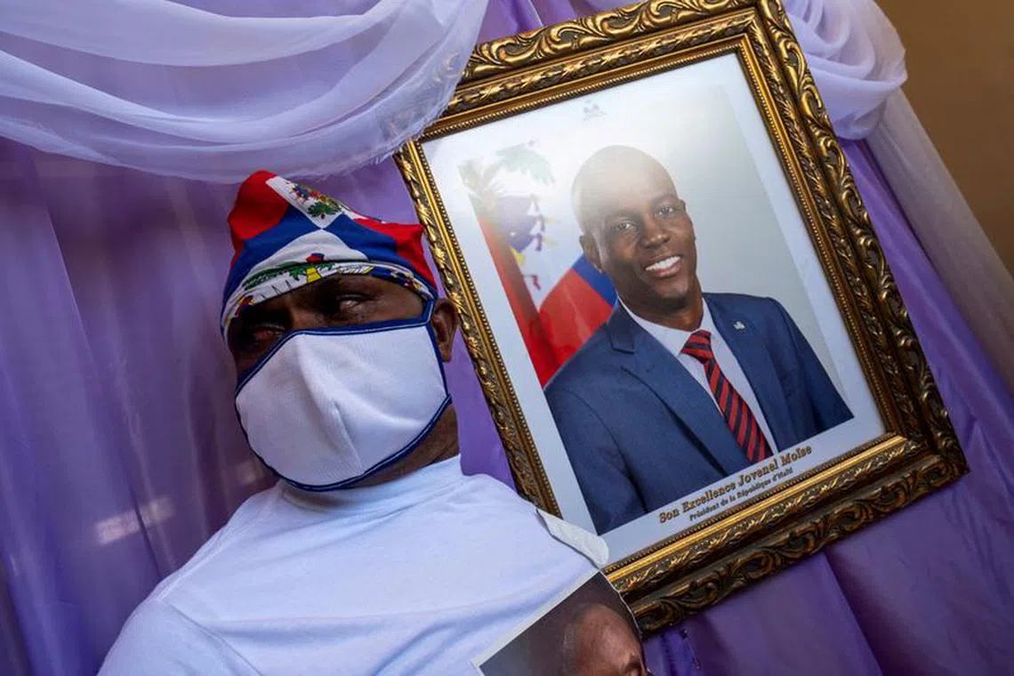 FILE PHOTO: A man stands next to a portrait of slain Haitian President Jovenel Moise placed on a memorial at the city hall in Cap-Haitien, Haiti July 22, 2021. REUTERS/Ricardo Arduengo/File Photo