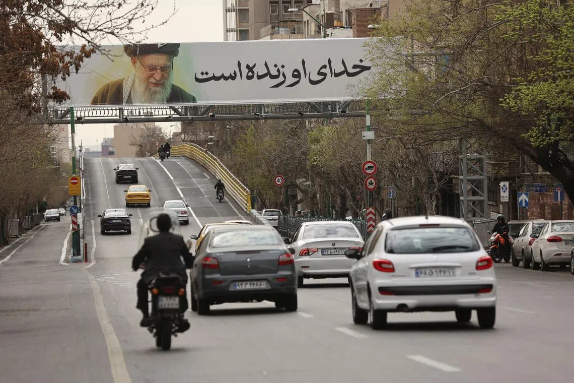 People drive near a banner of Iran's late Supreme Leader Ayatollah Ali Khamenei on a street, after he was killed in Israeli and U.S. strikes on Saturday, in Tehran, Iran, March 2, 2026. Majid Asgaripour/WANA (West Asia News Agency) via REUTERS