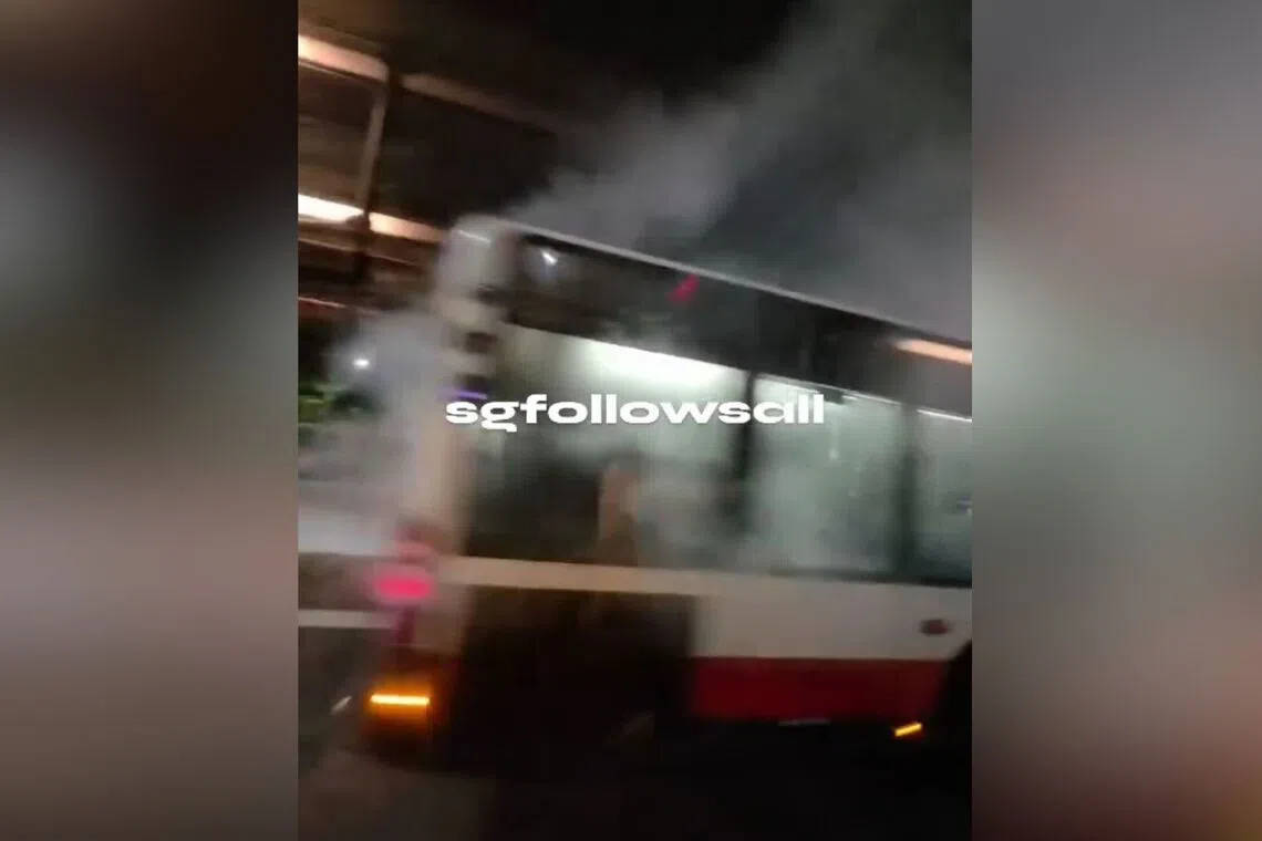 Smoke is seen rising from back half of the bus, which was stationary by the side of the road. 