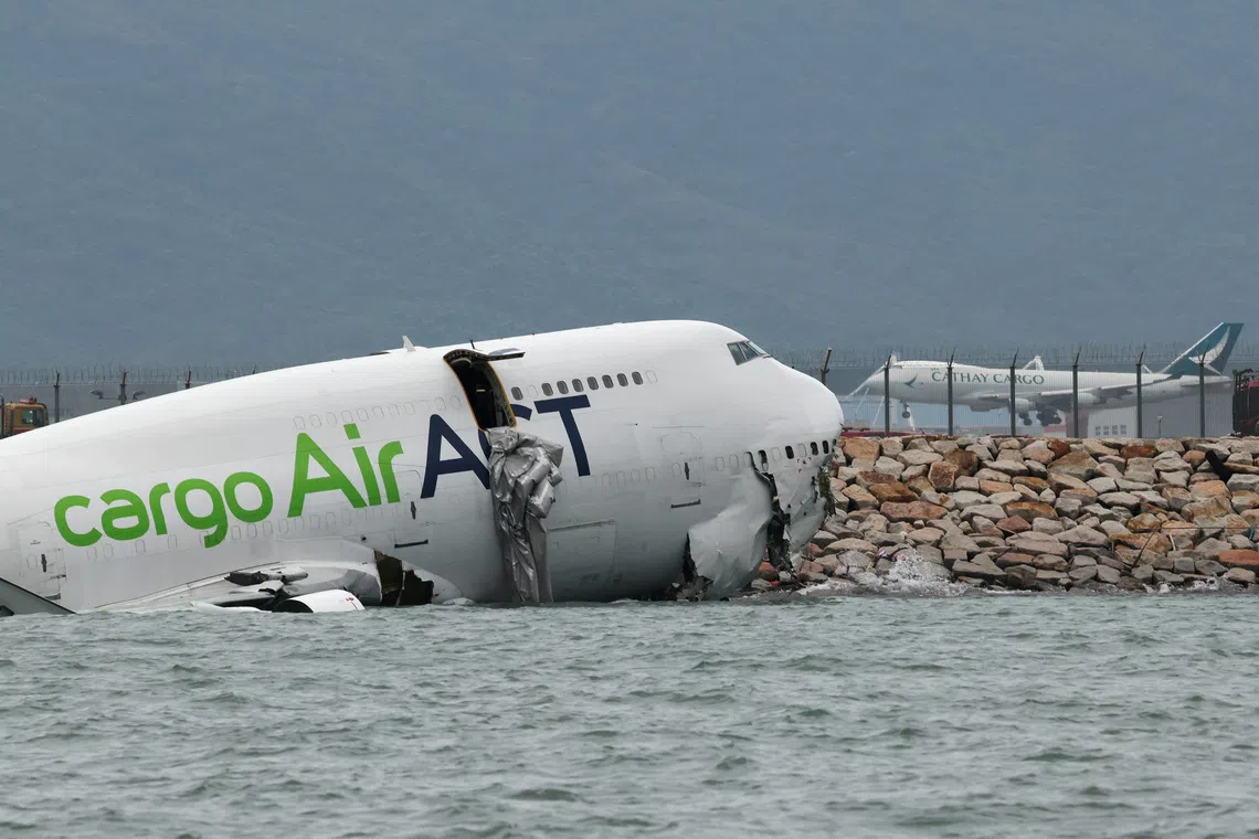 A cargo plane lies partially in the sea after veering off the runway during landing at Hong Kong International Airport in Hong Kong, China, October 20, 2025. REUTERS/Tyrone Siu