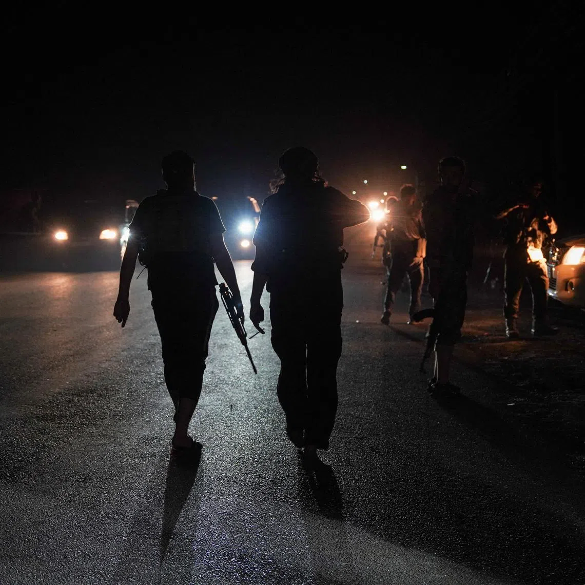 FILE PHOTO: Members of Syrian security forces walk on a road in Sweida countryside, as vehicles transporting other Syrian security forces make their way out of the predominantly Druze city of Sweida, Syria, July 16, 2025. REUTERS/Karam al-Masri/File Photo