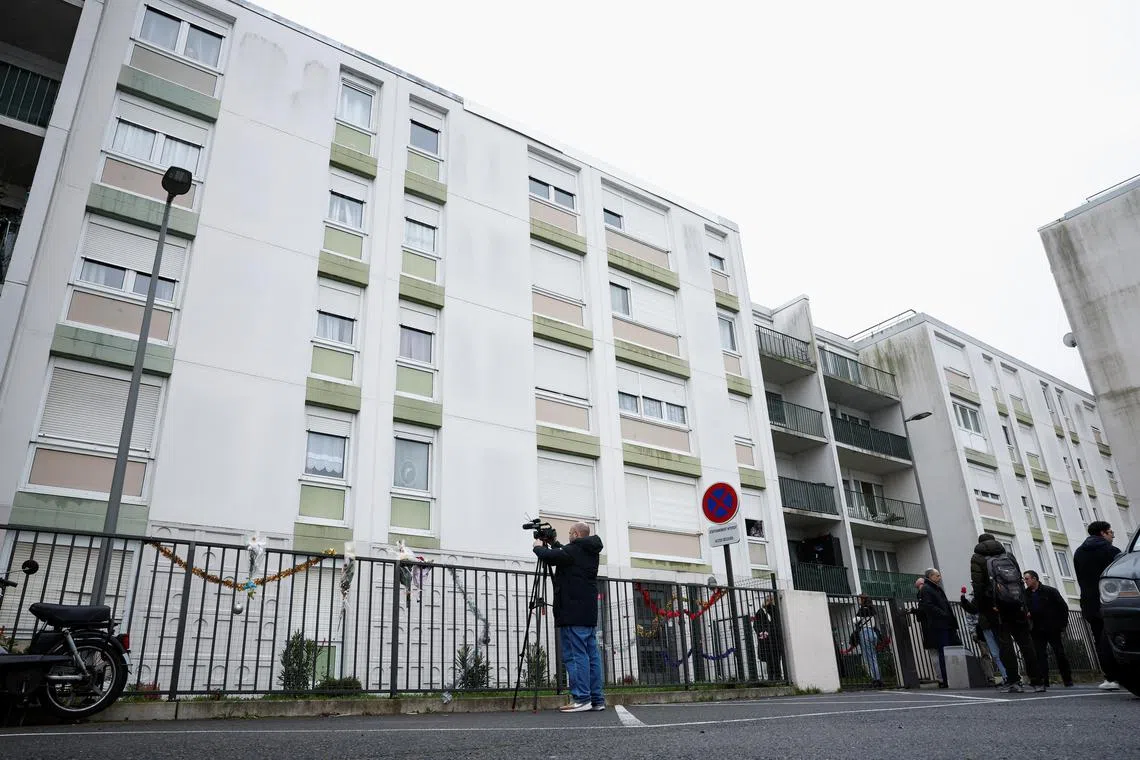 People stand outside the ground floor flat where the bodies of a woman and her four children were discovered in Meaux, north-east of Paris.