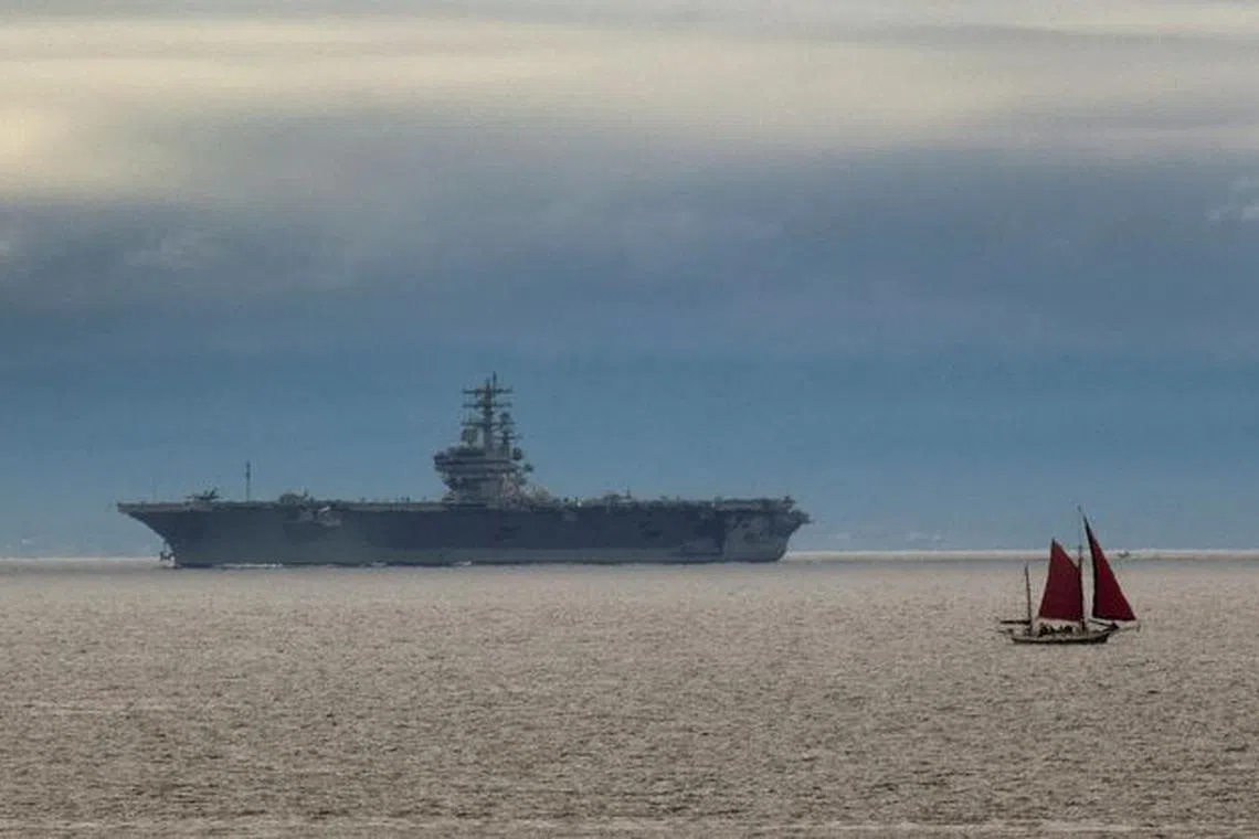 FILE PHOTO: The U.S. aircraft carrier USS Ronald Reagan arrives as small sailing ship heads out to sea in Victoria, British Columbia June 9, 2010.   REUTERS/Andy Clark/File Photo