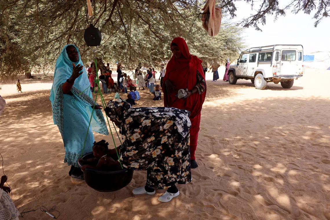 Image 4: A child is weighed by medical staff at a malnutrition station run by the International Rescue Committee (IRC) at the Iridimi refugee camp, northwest of Iriba in Wadi Fira province, eastern Chad, November 27, 2025. REUTERS/Amr Abdallah Dalsh  To match Special Report SUDAN-POLITICS/REFUGEES