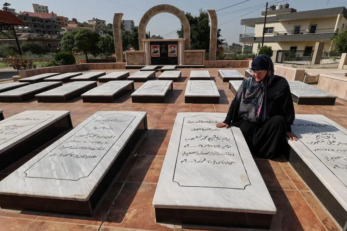 Rabab Youssef, 57, a survivor of the Israeli airstrike in 2006 that killed dozens, sits beside her daughter's grave in Qana, Lebanon October 24, 2023. REUTERS/Zohra Bensemra