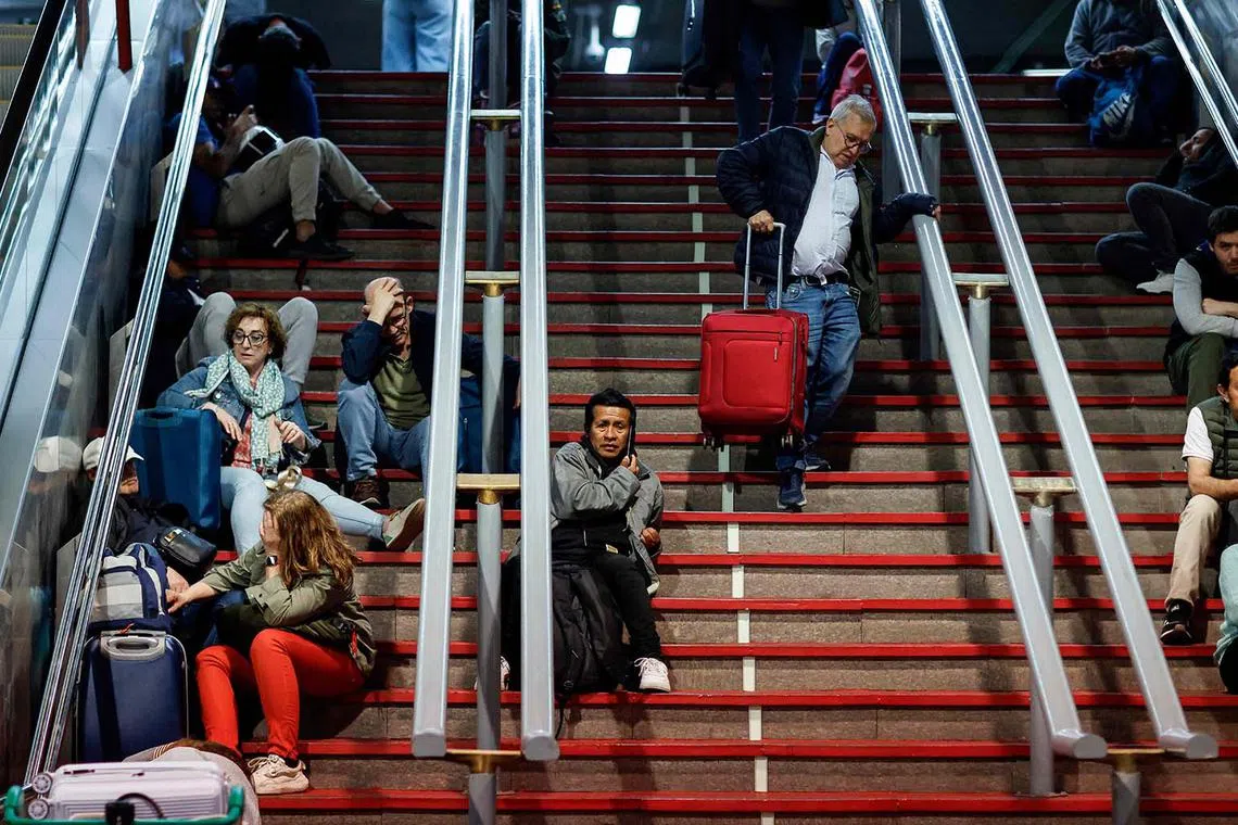 Travellers sitting on the stairs as they prepare to spend the night at the Atocha train station, following a massive power cut affecting the entire Iberian peninsula and the south of France, in Madrid, on April 28, 2025. 