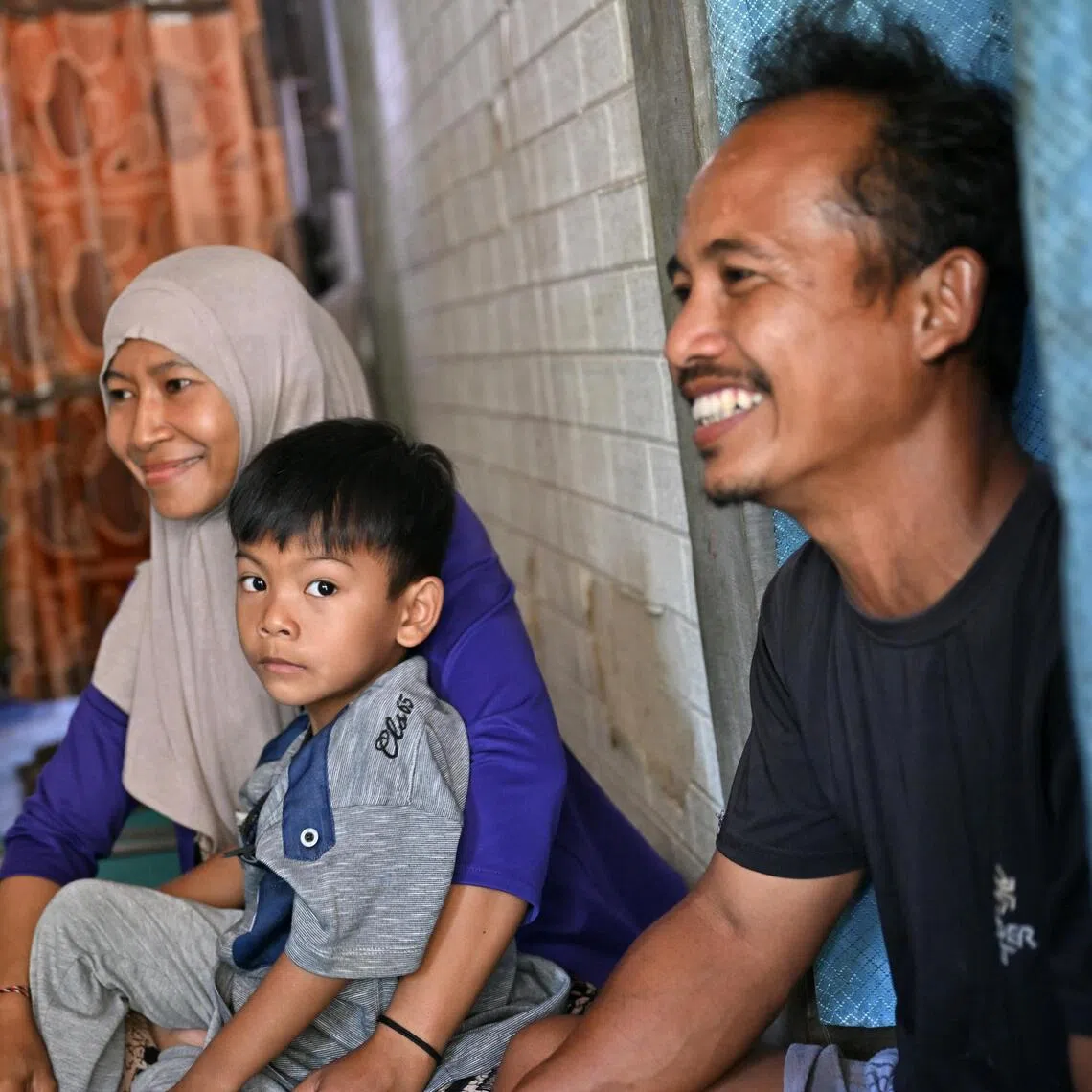 Adi Siswoyo, 43, with his wife, Asmarawati, 39, and their son, Rahmat Rafis Saputra, 5, at their home in Banjarbaru. The farmer’s household income has fallen substantially after wildfires scorched his farm.