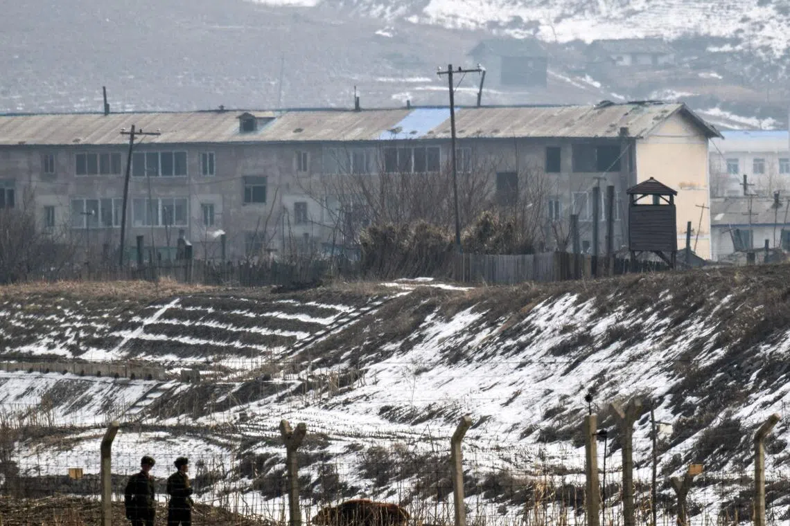 This photo taken on February 29, 2024 shows North Korean soldiers along the Yalu River in North Korea County Chunggang as seen from Linjiang in the province of Jilin, northeast China. North Korean soldiers gaze across an icy river towards China, occasionally descending from looming watchtowers to prowl border paths behind barbed wire and sharpened sticks.
This remote stretch of frontier was virtually inaccessible to reporters while Beijing and Pyongyang upheld some of the world's strictest pandemic-era travel curbs.
After the restrictions were unwound, an AFP team travelled to the region in late February -- peering back at the guards standing sentry at the entrance to the secretive nuclear nation.
Between rusting factories and peeling housing blocks were glimpses of everyday life, as North Koreans eked out their living by hauling timber and burning crop fields.
In one town, two goods trucks waited patiently on a bridge into China -- a sign of resumption in the cross-border trade crucial to Pyongyang's moribund economy.
North Korea's chronic food shortages are believed to have grown more acute during the pandemic, and campaigners say authorities have strengthened border defences to prevent escapes to its vast, wealthy neighbour.
Beyond the eagle-eyed guards, portraits of the ruling Kim dynasty watched over the populace, while monumental propaganda banners lauded their socialist ideology.
One slogan, written in huge red and white letters on a hillside, simply blared: "Our country is the best!" (Photo by Pedro PARDO / AFP) / To go with China-NKorea-politics, REPORTAGE