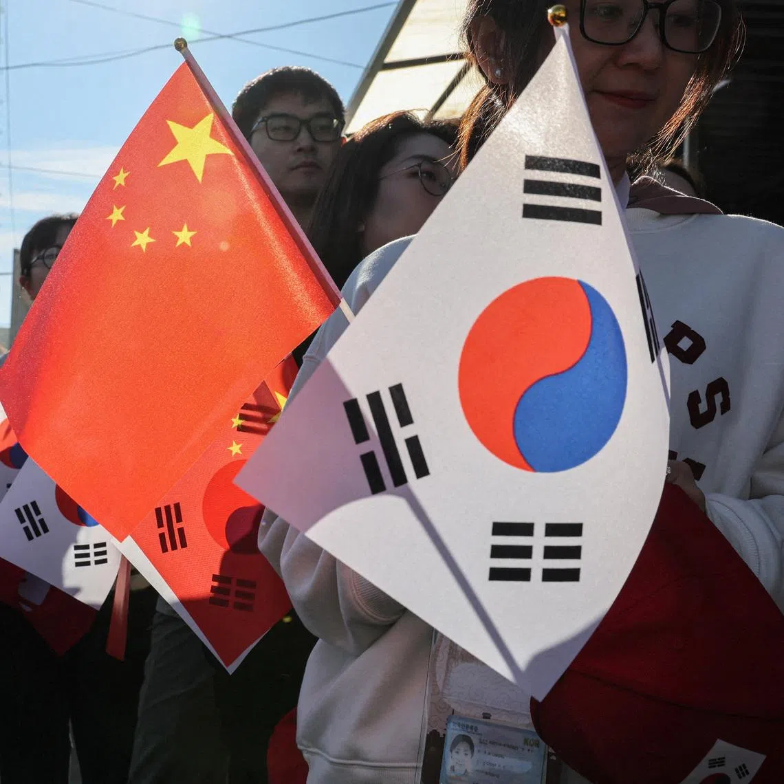 FILE PHOTO: Pro-China supporters hold China and South Korea flags near Gimhae International Airport ahead of a bilateral meeting between U.S. President Donald Trump and Chinese President Xi Jinping on trade tensions and bilateral relations, on the sidelines of the Asia-Pacific Economic Cooperation (APEC) Summit, in Busan, South Korea, October 30, 2025. REUTERS/Tyrone Siu/File Photo