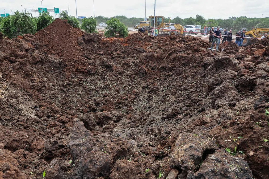 Members of Israeli security services inspecting a crater near a road outside Israel's Ben Gurion airport after a missile launched from Yemen struck the area on May 4.