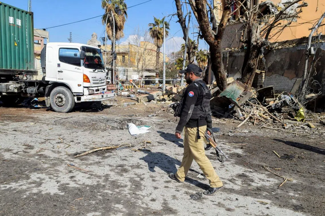 A police officer walks past damage at the site, after militant attacks, in Quetta, Pakistan on Feb 1.