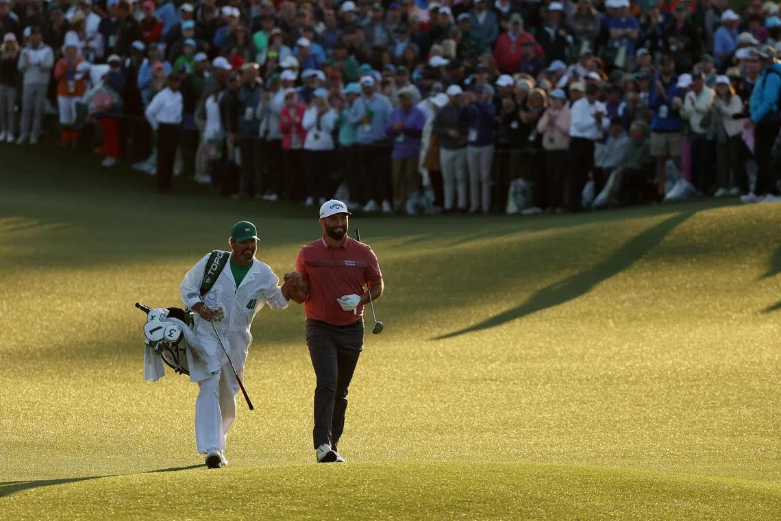 Masters champion Jon Rahm of Spain and his caddie Adam Hayes walk up the 18th fairway on Sunday. 