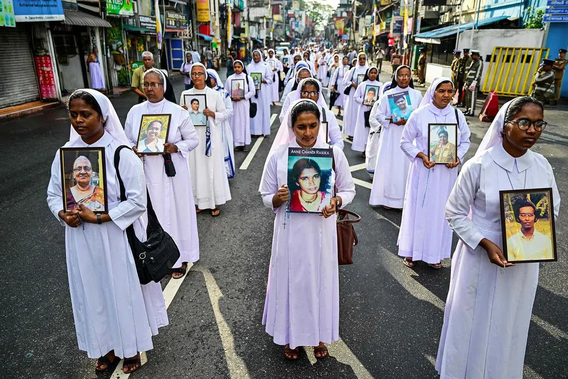 TOPSHOT - Catholic nuns carry portraits of victims of the 2019 Easter Sunday bombings as they pay tribute to mark the 6th anniversary of the suicide attacks, during a silent march outside the St. Anthony's church in Colombo on April 21, 2025. The head of Sri Lanka's Roman Catholic church, Cardinal Malcolm Ranjith, led the march in the capital where he presided over a multi-religious ceremony for the 279 victims, including 45 foreigners. Several investigations into the bombings have concluded that the attacks were carried out by a homegrown jihadist group that claimed affiliation with the Islamic State group. (Photo by Ishara S. KODIKARA / AFP)