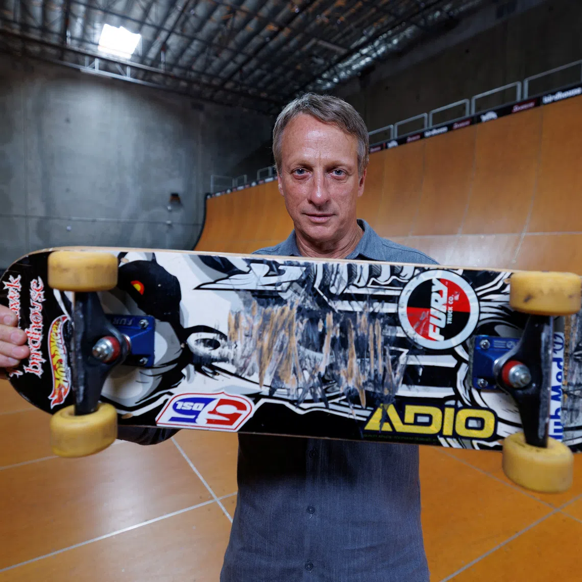 Tony Hawk holds the skateboard he used to land the first-ever \"900\" at the 1999 X Games, a milestone that transformed skateboarding from subculture to global sport and made Hawk its defining icon. The Birdhouse \"Falcon 2\" board helped etch the trick into history and will be auctioned by Julien's to help raise money for his charity \"The SkatePark Project\" in Vista,  California, U.S., August 19, 2025.  REUTERS/Mike Blake