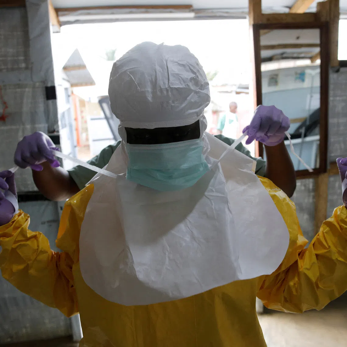 FILE PHOTO: A health worker puts on Ebola protection gear before entering the Biosecure Emergency Care Unit (CUBE) at the ALIMA (The Alliance for International Medical Action) Ebola treatment centre in Beni, in the Democratic Republic of Congo, March 31, 2019. Picture taken March 31, 2019. REUTERS/Baz Ratner/File Photo