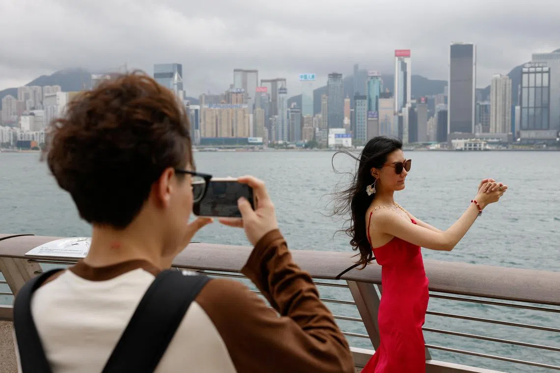 Laura Li, 28, poses for photos in front of Victoria Harbour, a day ahead of the Chinese Labour Day 'Golden Week' holidays, in Hong Kong, China April 30, 2024. REUTERS/Tyrone Siu