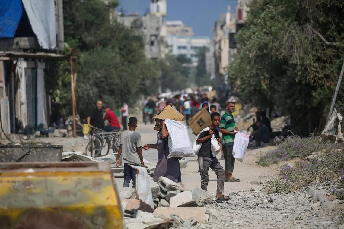 Displaced Palestinians hauling food parcels and other items they managed to get from a GHF aid distribution point, in the central Gaza Strip on July 26.