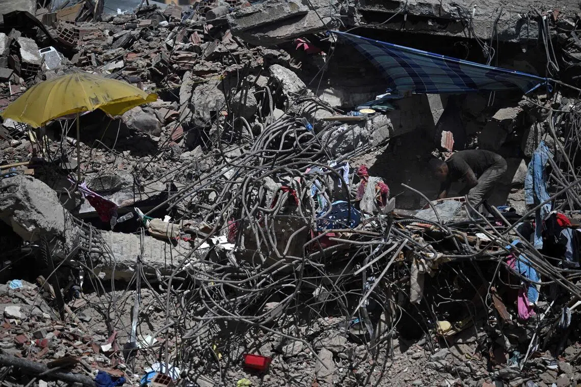 TOPSHOT - A man removes debris while searching for bodies under the rubble of a building destroyed by the June 24 earthquakes in Caraballeda, Venezuela, on July 17, 2026. More than three weeks after the double earthquake in Venezuela, the official death toll has surpassed 5,000, according to an updated count released by authorities on July 17. (Photo by Raul ARBOLEDA / AFP)