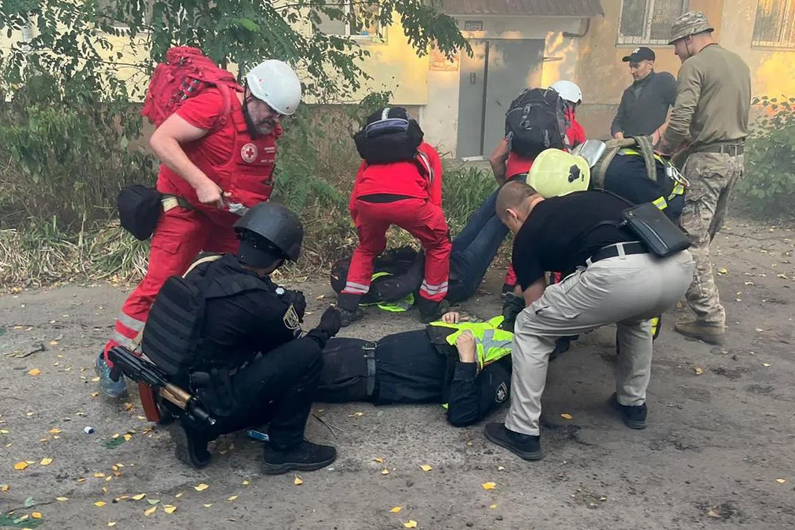 Ukrainian medics and law enforcement officers providing assistance to a police officer, following a drone attack in Sumy, on Sept 28.