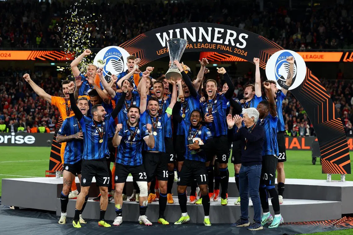 Atalanta's Berat Djimsiti and Ademola Lookman lift the trophy with teammates after winning the Europa League final.