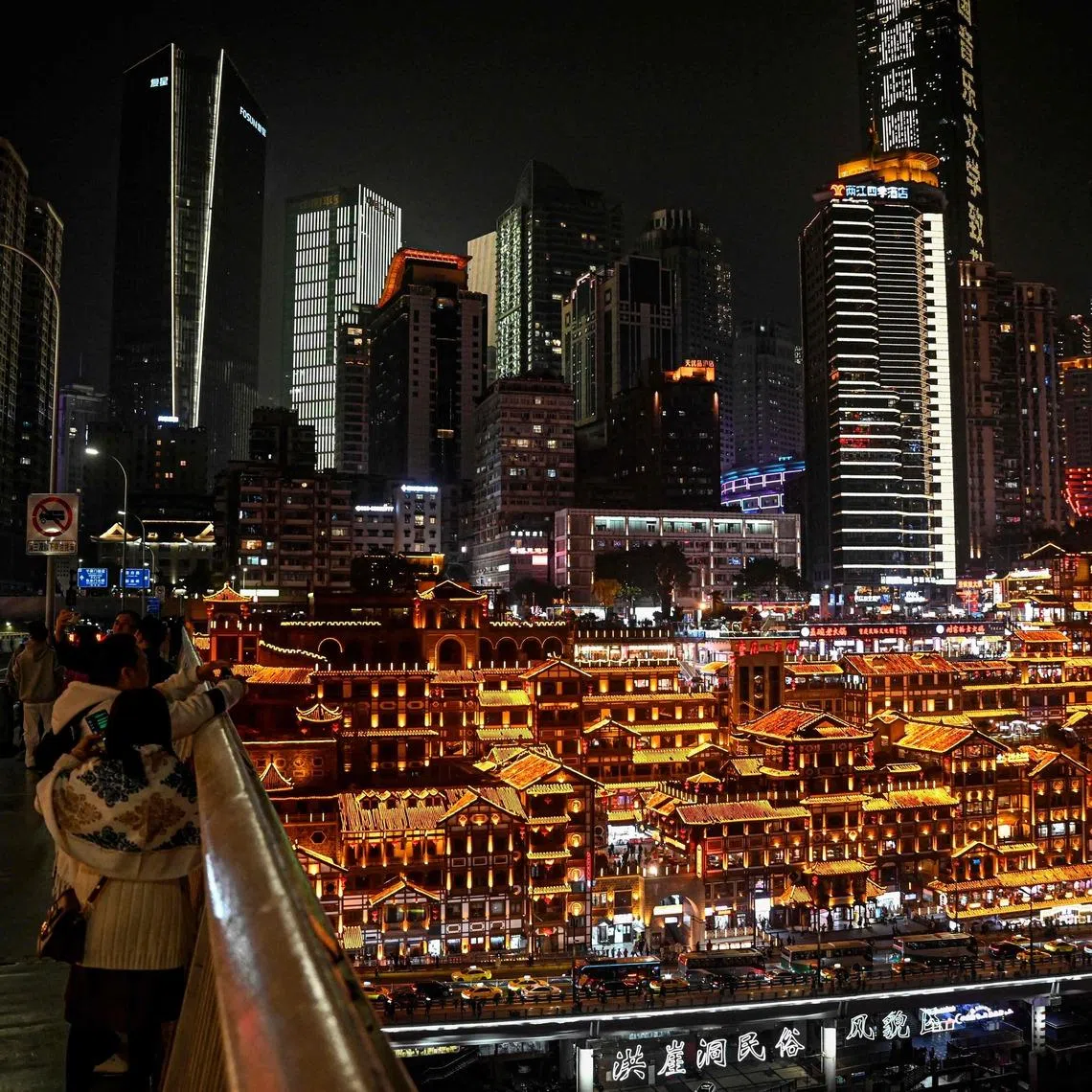 People enjoy the night lights of Hongya Cave from the Qiansimen Bridge, in southwestern China's Chongqing municipality on December 15, 2025.