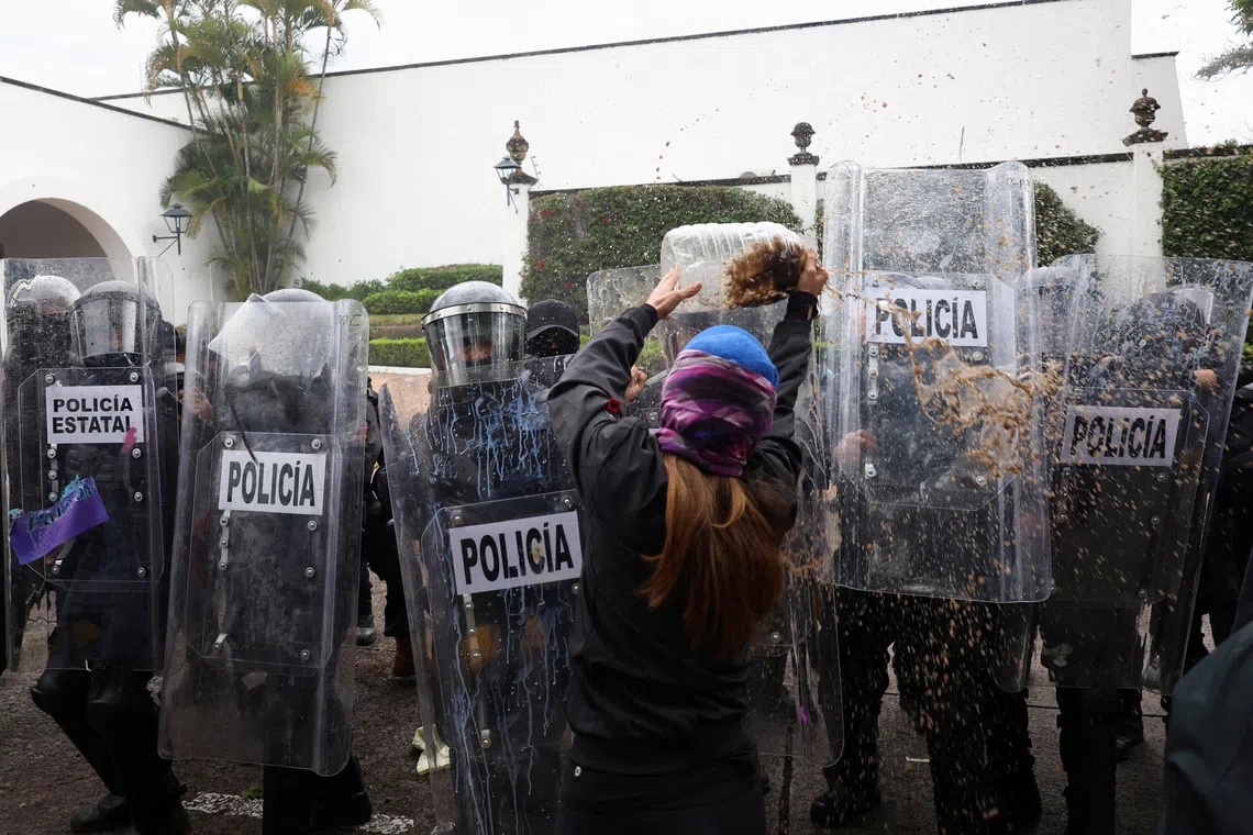 A protester throws dirty water at state riot police during a demonstration demanding clean water after weeks of residents' complaints about discolored and foul-smelling water in parts of the metropolitan area, outside Casa Jalisco, the official residence of the state governor, in Guadalajara, Mexico, October 11, 2026. REUTERS/Stringer