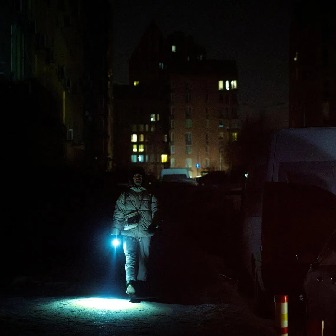 A man carries a torch as he walks a dark street in a neighborhood left without electricity after recent Russian strikes on the capital’s civilian infrastructure, amid Russia's attack on Ukraine, during sub-zero temperatures in Kyiv, Ukraine January 24, 2026.  REUTERS/Thomas Peter