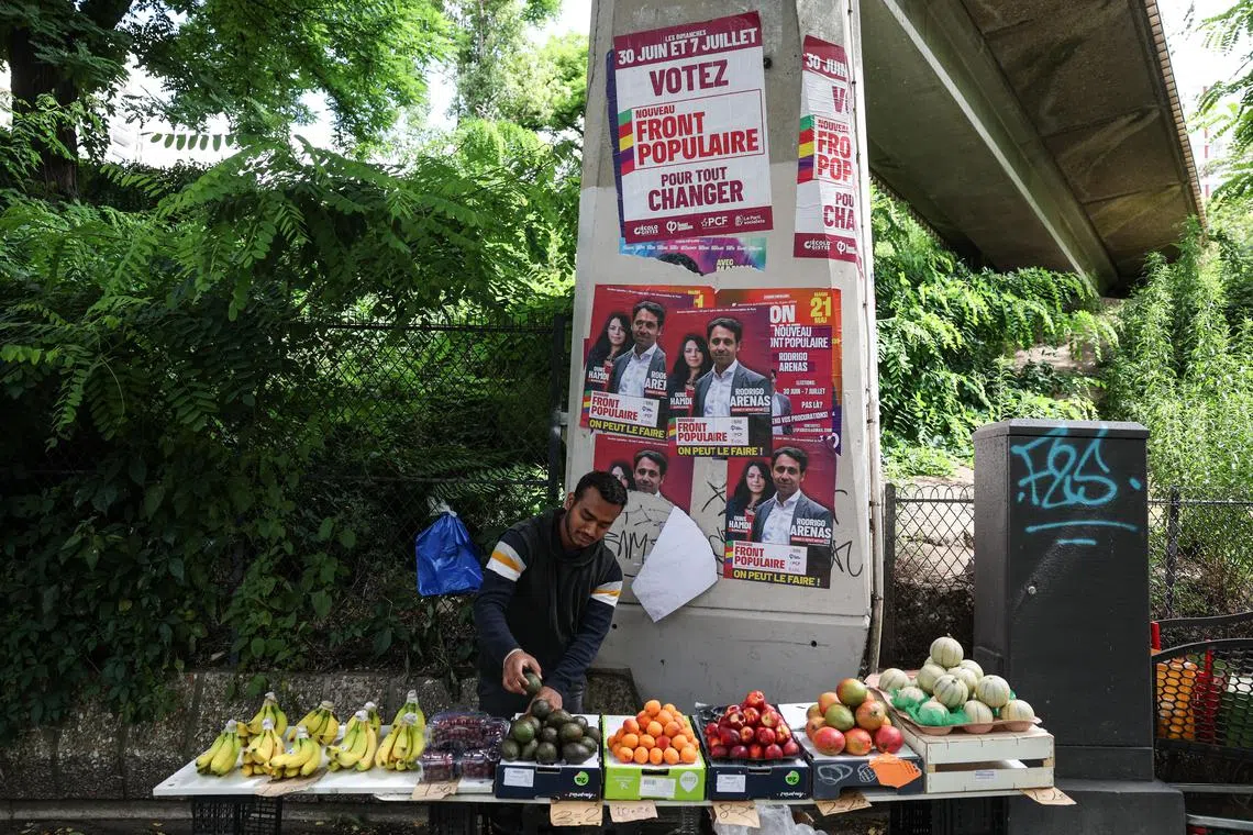 epaselect epa11456705 A street vendor stands next to posters of Nouveau Front Populaire 'The New Popular Front' candidates for parliamentary elections in Paris, France, 04 July 2024. The second round of the French parliamentary elections is to be held on 07 July 2024.  EPA-EFE/MOHAMMED BADRA