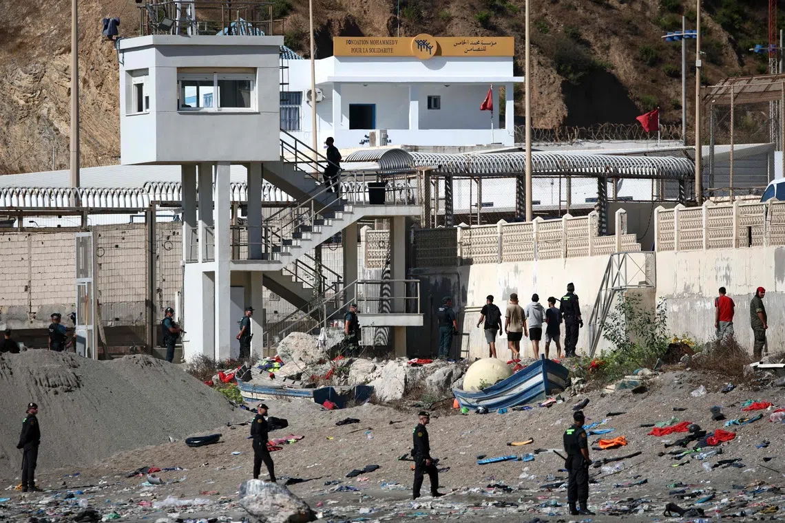 Some migrants arrive at the border post with the intention of crossing back into Morocco as members of the Spanish armed forces keep watch over the area in the Spanish enclave of Ceuta on August 2.