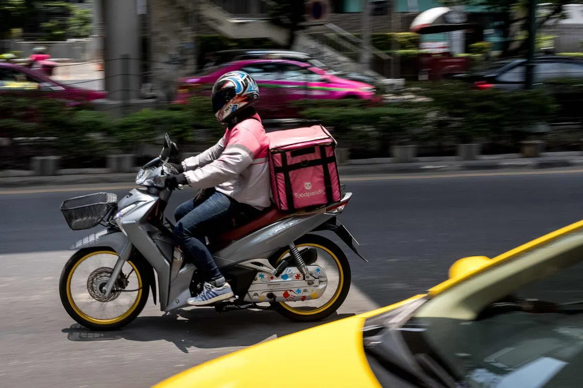 A foodpanda delivery driver rides his motorcycle in Bangkok on May 4, 2021, as restaurants have been ordered to offer takeaway only amid the latest Covid-19 coronavirus wave in Thailand. (Photo by Jack TAYLOR / AFP)