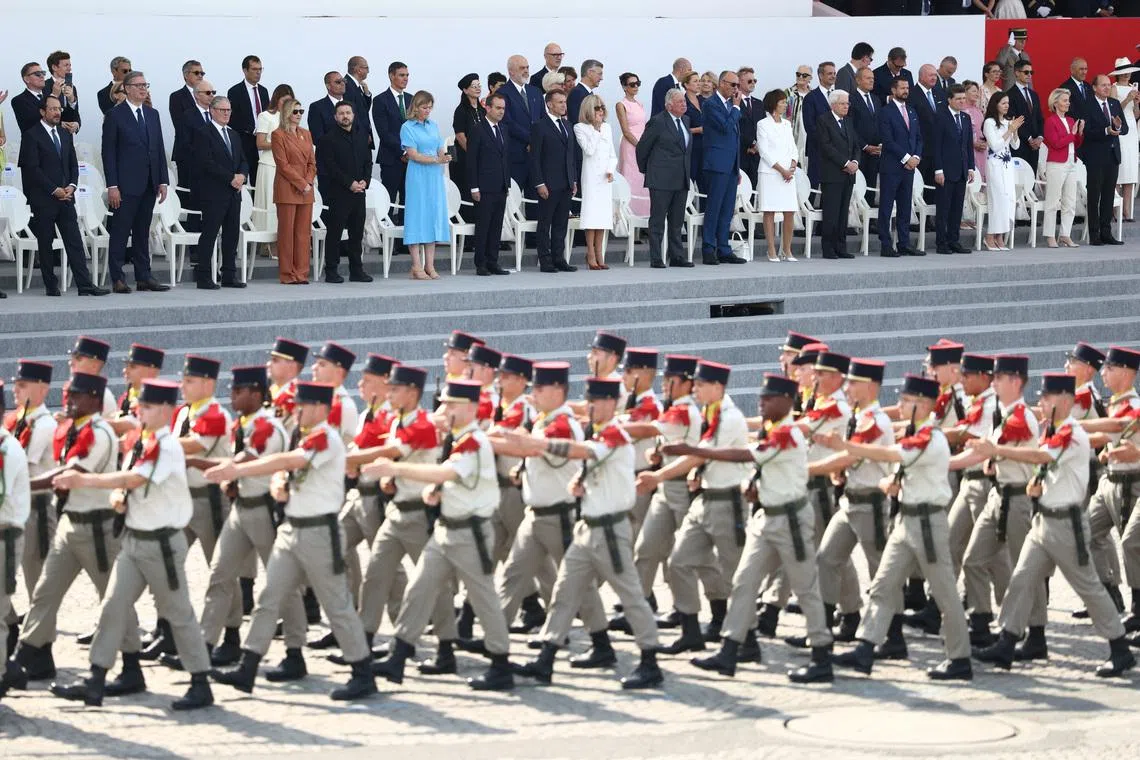 French President Emmanuel Macron, his wife Brigitte Macron, Ukraine's President Volodymyr Zelenskiy and his wife Olena Zelenska, Heads of State and Government of the Coalition of the Willing and members of the French government attend the annual Bastille Day military parade on the Place de la Concorde in Paris, France, July 14, 2026. REUTERS/Tom Nicholson