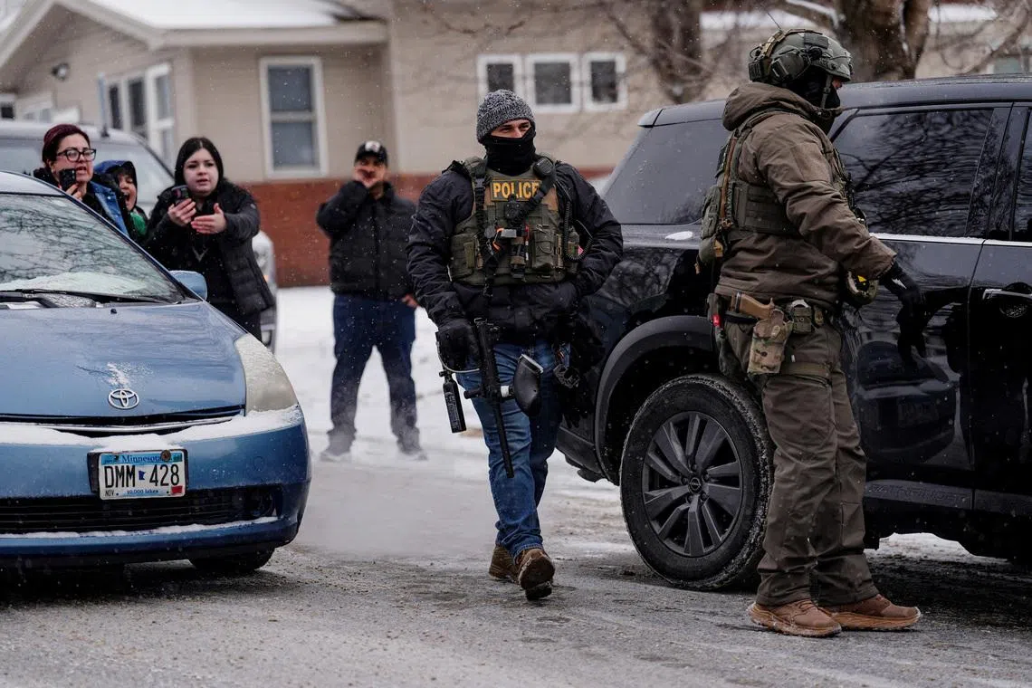 People react and record with their phones while ICE agents and other law enforcement officers detain a man after conducting an immigration raid at his home in St. Paul, Minnesota, U.S., days after an ICE agent fatally shot Renee Nicole Good, January 18, 2026. REUTERS/Leah Millis