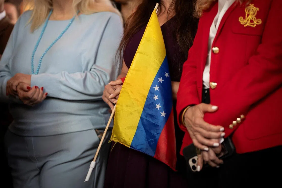 A woman holds a Venezuelan flag during a press conference on the U.S. strikes in Venezuela, in Doral, Miami-Dade County, Florida, U.S., January 5, 2026. REUTERS/Marco Bello
