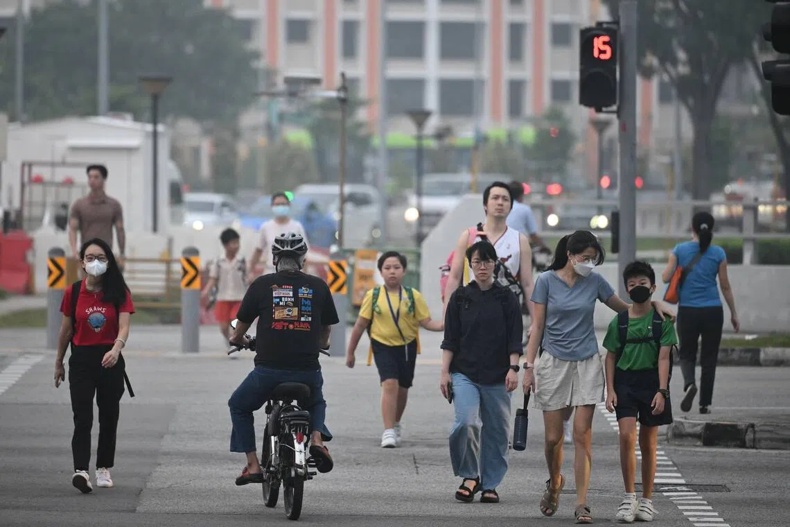 Pedestrians wearing face masks and crossing Tampines Avenue 1 towards Block 803 Tampines Avenue 4 at 7am on Oct 16.