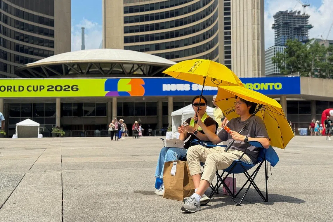 Two football fans watch the match between Ivory Coast and Norway at Nathan Phillips Square in Toronto on June 30.