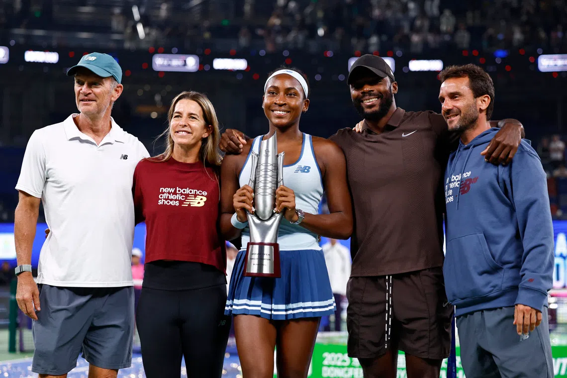 Tennis - WTA 1000 - Wuhan Open - Optics Valley International Tennis Center, Wuhan, China - October 12, 2025 Coco Gauff of the U.S. poses with the trophy and team after winning the final against Jessica Pegula of the U.S. REUTERS/Tingshu Wang