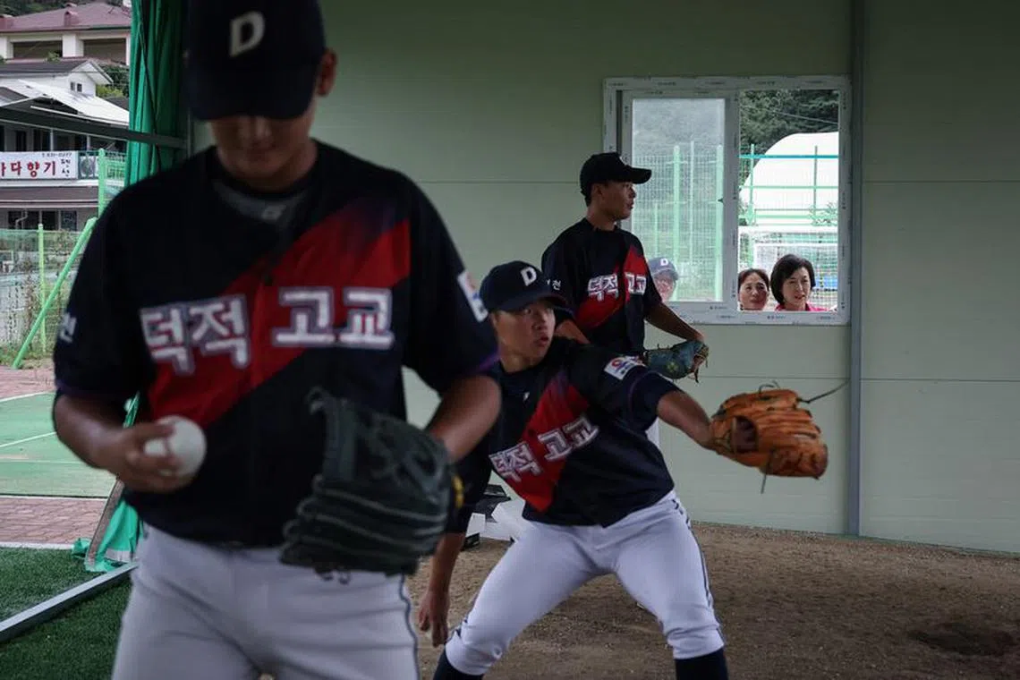 Local people watch An Seung-han, 17, An Seung-young, 16, and Bang Jun-young, members of the Deokjeok High School baseball team, as they take part in a practice session, on Deokjeok island in Incheon, South Korea, September 14, 2023. Dreaming of making it big in baseball, teenage brothers An Seung-han and An Seung-young travelled hundreds of miles away from home to remote Deokjeok island, where the sport and their team, are now the closest thing they have to a family. The boys are among a few dozen teenagers who have left the bright lights of some of South Korea's biggest cities to join a specialised sports academy set up by Kim Hak-yong, former manager of the elite Dongguk University team that has produced scores of players in the national KBO major league. \"If I work hard here, I can be a main player, so I'm working even harder. If I keep doing well, I can also become a professional baseball player,\" 16-year-old Seung-young, the younger brother, said during a training session. REUTERS/Kim Hong-Ji