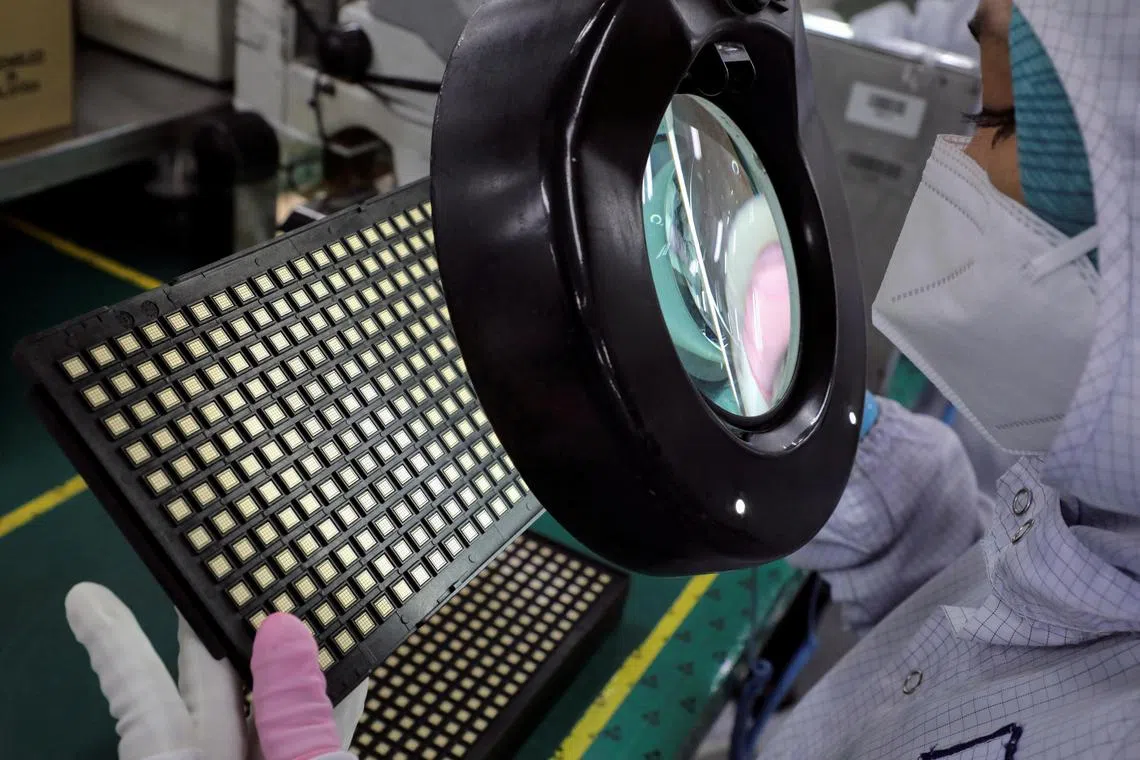 A worker inspects semiconductors at chip packaging firm Unisem in Ipoh, Malaysia.