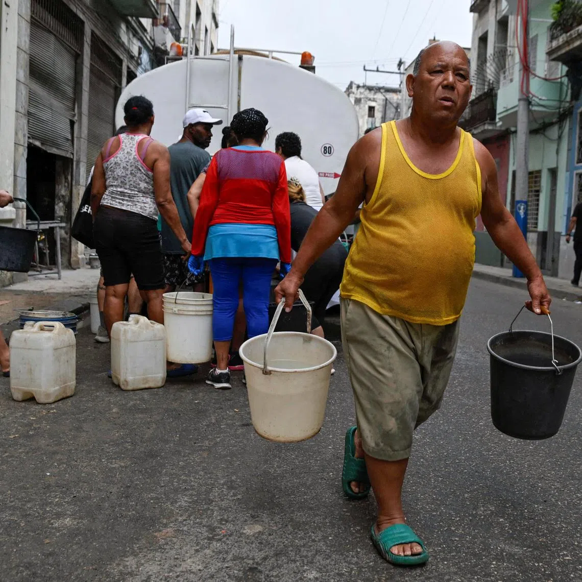 A man carries two buckets of water as severe fuel shortages have disrupted water pumping and distribution, in Havana, Cuba March 19, 2026. REUTERS/Norlys Perez