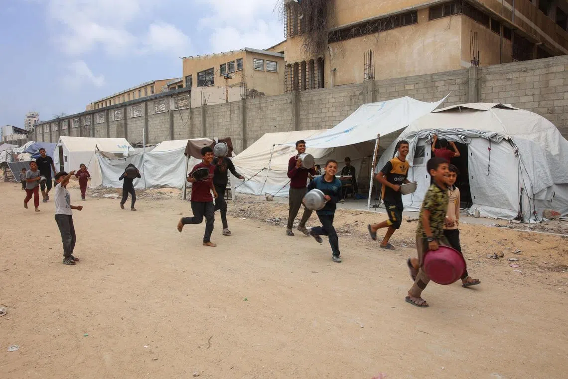 Palestinian boys carrying containers run towards a charity kitchen in Gaza City on May 12.
