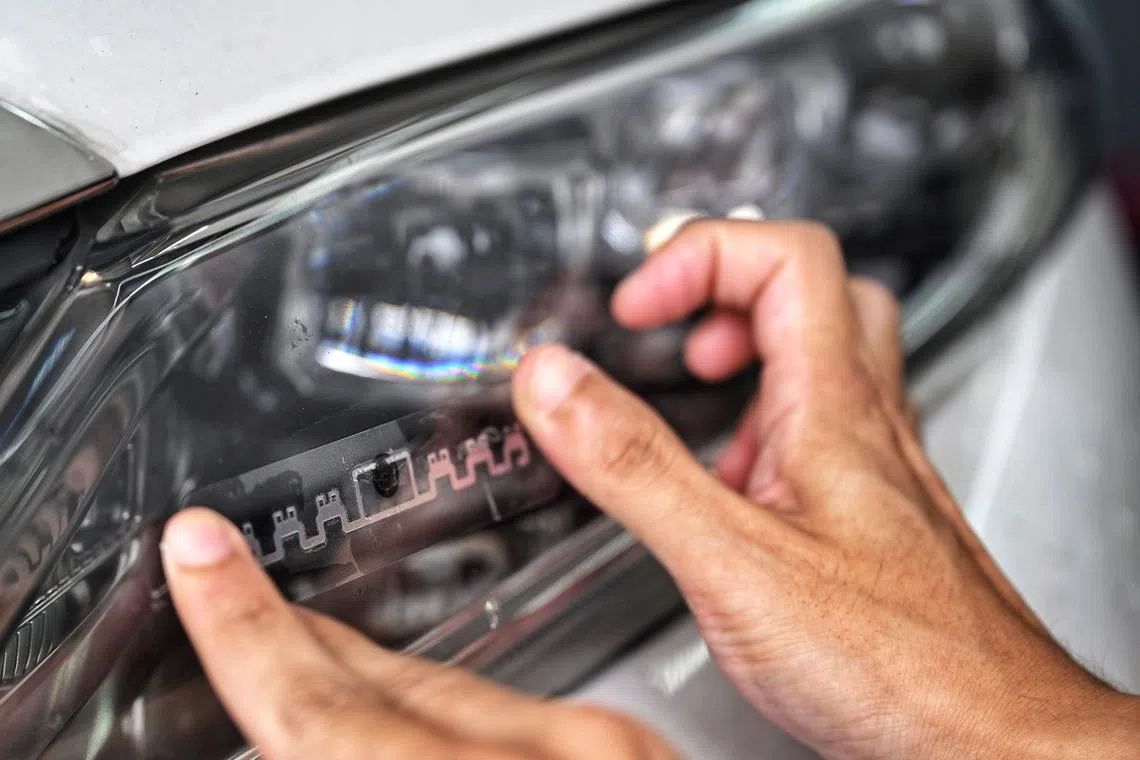 A VEP RFID tag being installed on a vehicle headlight at the VEP office in Woodlands on Oct 1.