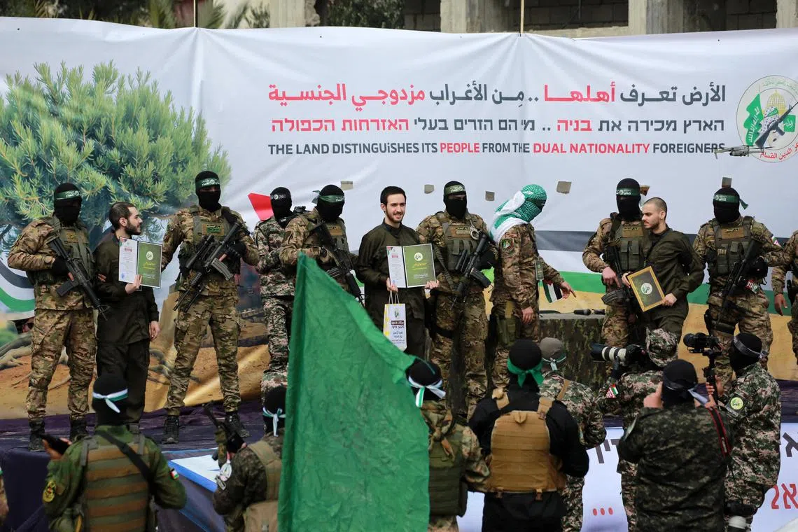 Hamas militants parade newly-released Israeli hostages (from left) Elia Cohen, Omer Shem Tov and Omer Wankert on stage in Nuseirat in the central Gaza Strip, as part of the seventh hostage-prisoner release on Feb 22. 